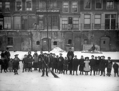 810573 Afbeelding van een groep kinderen op het ijs van de bevroren Oudegracht te Utrecht; op de achtergrond de huizen ...